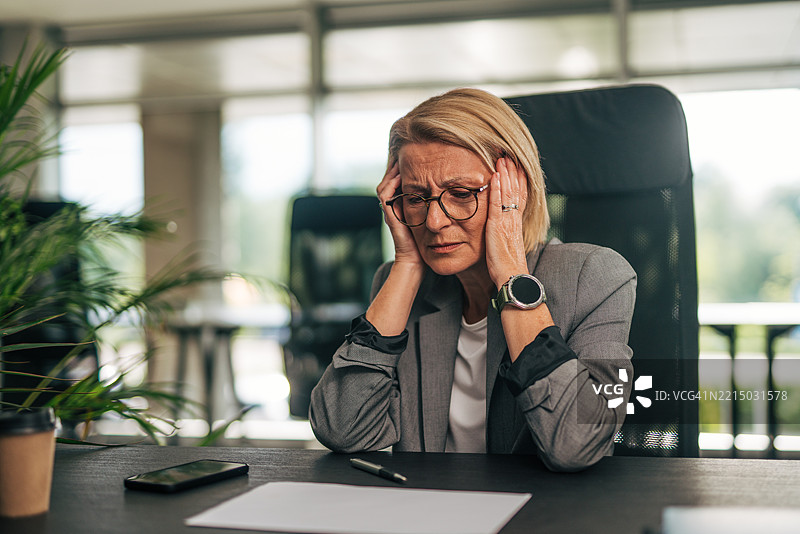 感到压力的高级女商人在工作场所头痛图片素材
