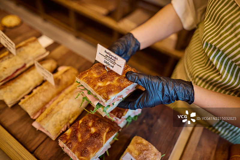 女售货员在面包店里提供美味的三明治图片素材