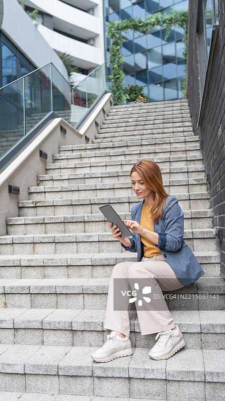 专注的女商人坐在楼梯上使用平板电脑图片素材