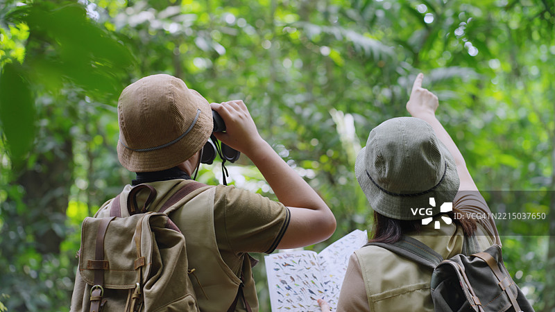 亚洲家庭在环保森林中使用指南书观察鸟类图片素材
