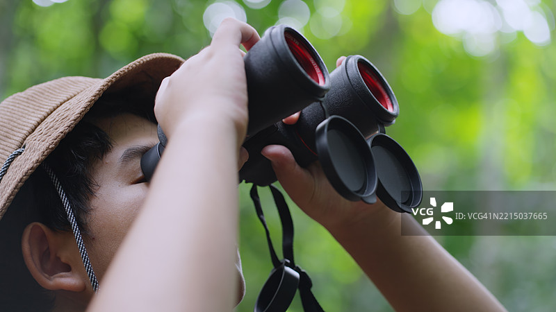 特写：亚洲少年在森林中仰望观鸟图片素材
