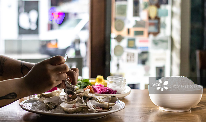 一双手在明亮的餐厅里准备生蚝图片素材