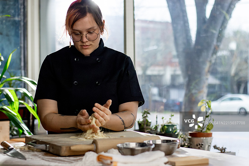 一位面包师在窗边用双手揉面团图片素材