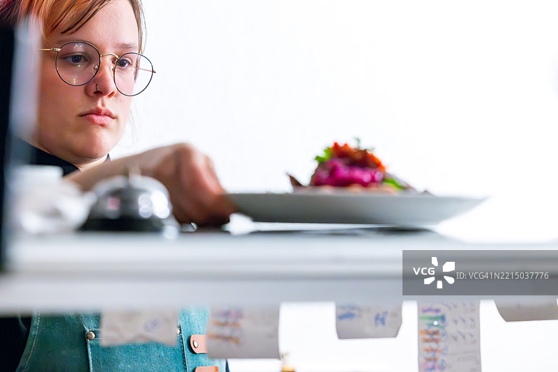 一位厨师将一道色彩鲜艳的菜肴放在柜台上准备上菜图片素材