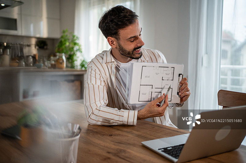 建筑师在家中视频通话时展示蓝图图片素材