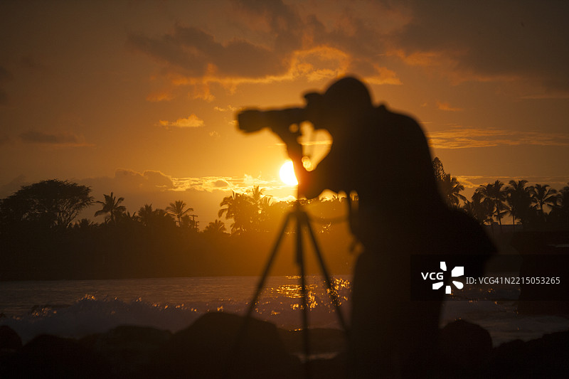 在落日余晖下，三脚架前的摄影师剪影图片素材