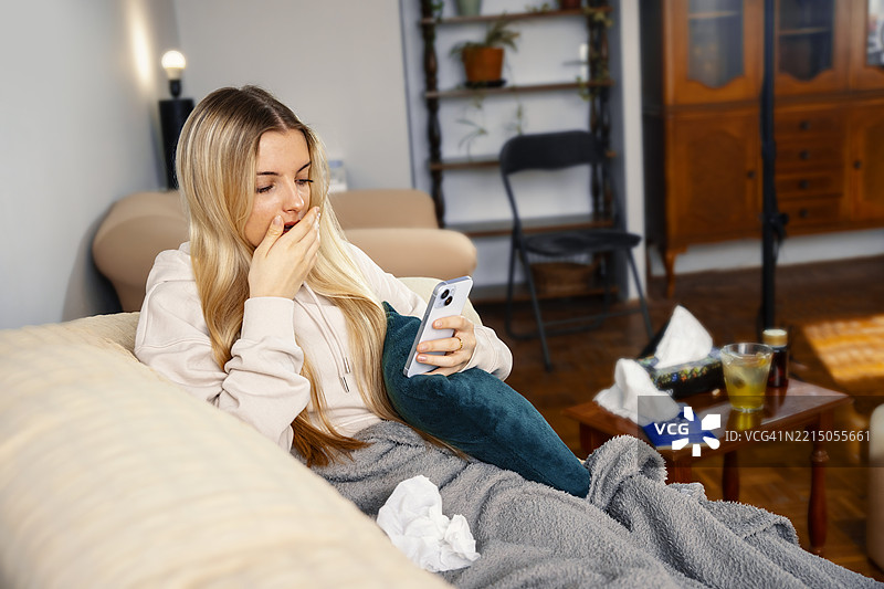 担心和惊讶的少女在家中看着智能手机图片素材
