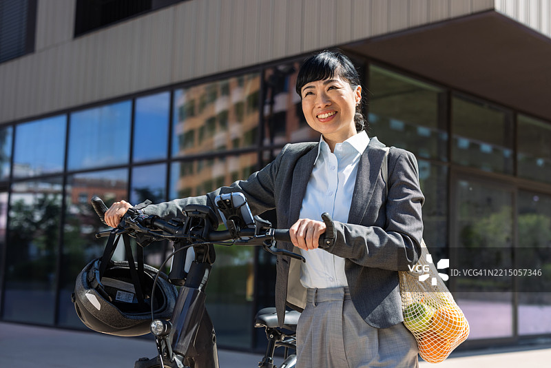 现代城市环境中的女商人与电动自行车图片素材