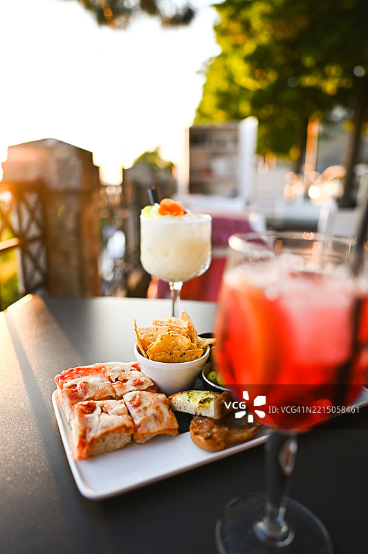 在日落时分享受开胃酒、比萨、玉米片和鸡尾酒图片素材