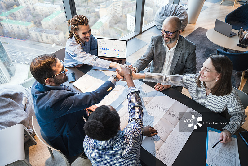 团队在现代办公室环境中庆祝商业成功，窗外景色明亮。图片素材