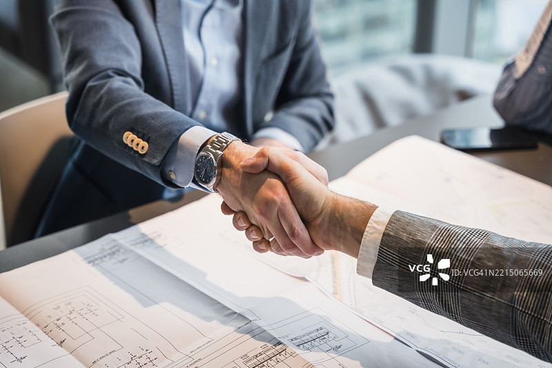 象征商业伙伴关系和合作的专业握手，场景为办公室环境图片素材