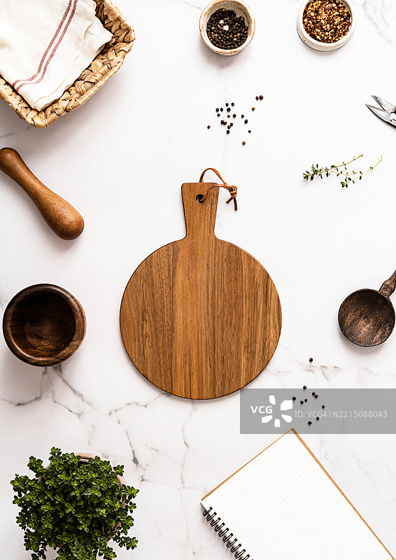 厨房背景的俯视框架，白色大理石台面和中央木板上的餐具和香草，适合用于文本或产品广告。图片素材