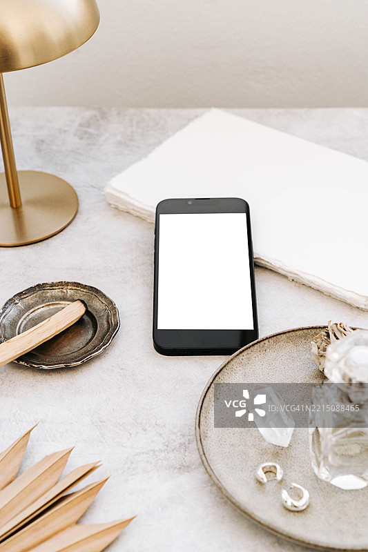 桌子上的空白屏幕智能手机、笔记本、巴洛圣木、鼠尾草束和水晶图片素材