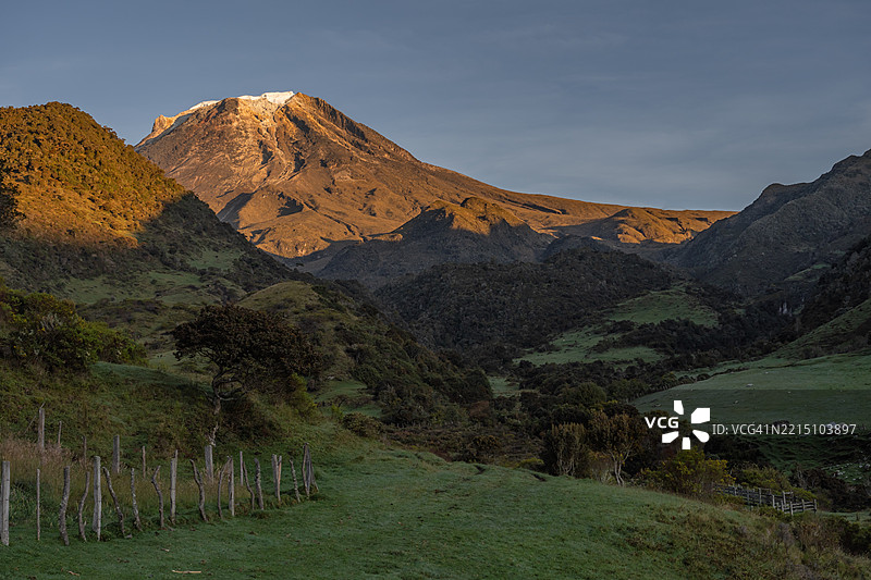 日出时分，哥伦比亚安第斯山脉的托利马雪山呈现出金色和绿色的自然色调。图片素材