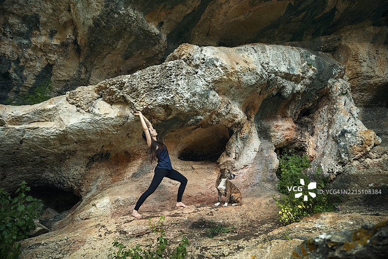 年轻女性在户外与她的狗一起练太极，一位穿着运动服的女性在山中锻炼。图片素材