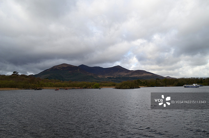 云彩悬浮在山脉上方，旁边是一条水道图片素材