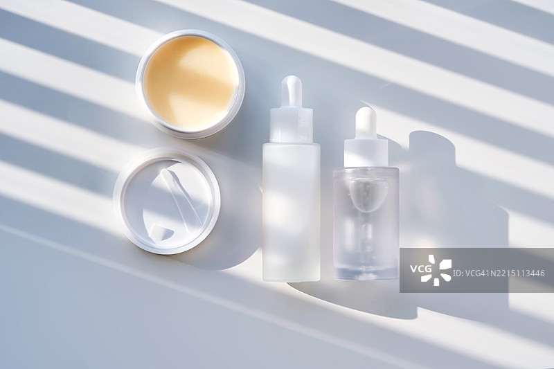 一组护肤化妆品在白色背景上，带有阴影条纹。图片素材
