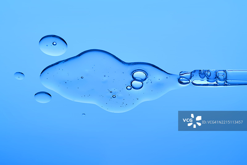 美丽的精华液质地与蓝色背景上的滴管图片素材
