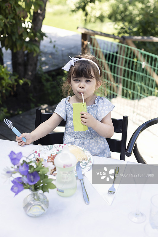 女孩坐在后院的椅子上喝果汁的肖像图片素材