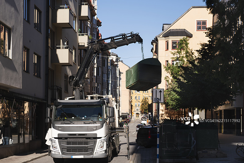 垃圾车在城市街道上收集垃圾桶图片素材