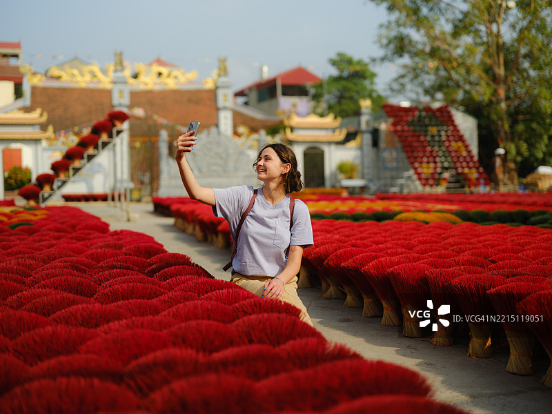 在越南河内的香火村，一位女性用智能手机拍照。图片素材