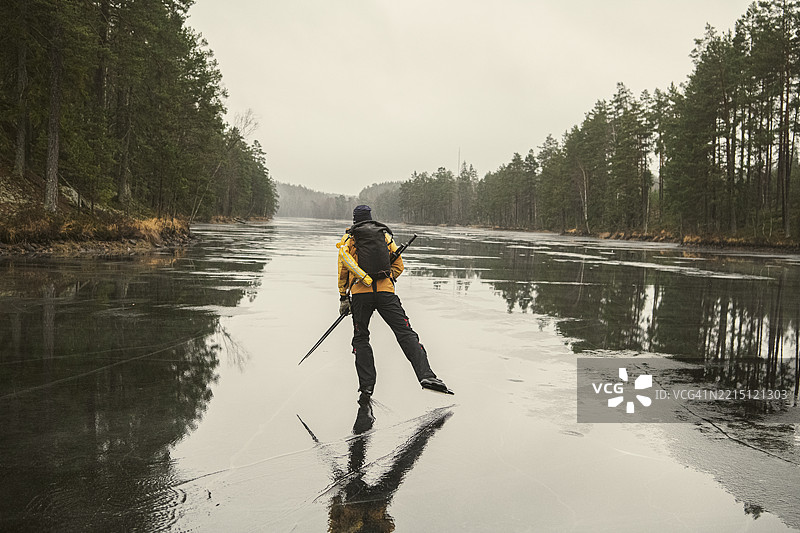 早晨，男子在冰冻湖面上滑冰的背影图片素材