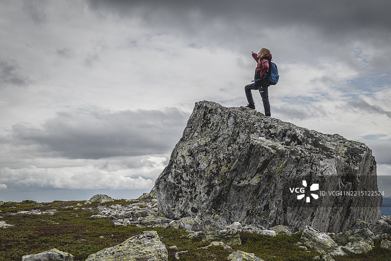 女人站在岩石上指向天空图片素材