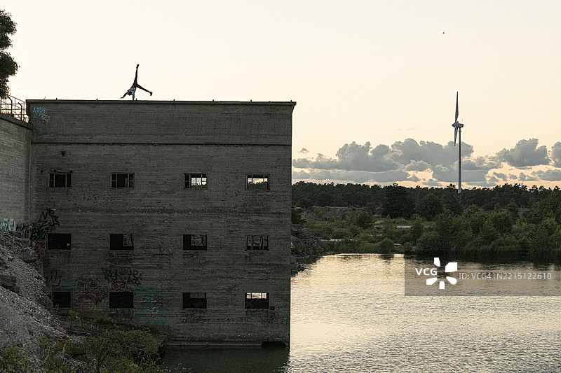 在废弃建筑顶上，模糊不清的人在黎明时分做侧手翻图片素材