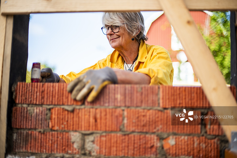 微笑的女性在房屋翻新时砌砖图片素材