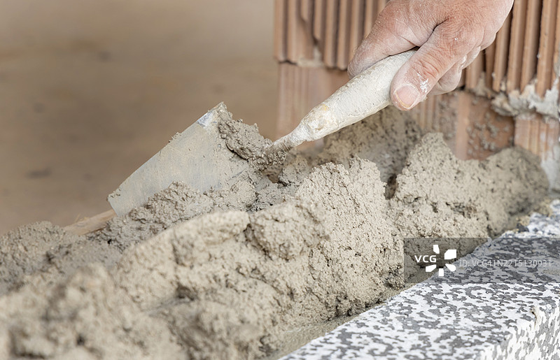 肮脏的工匠手用抹子将水泥或石膏涂抹在墙上，特写建筑细节图片素材