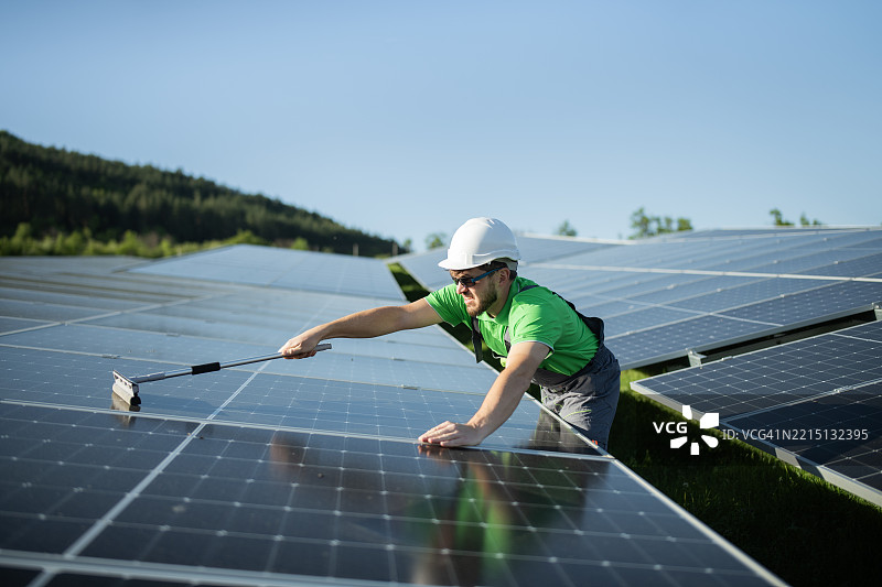 用窗户清洁剂清洁太阳能电池板。图片素材