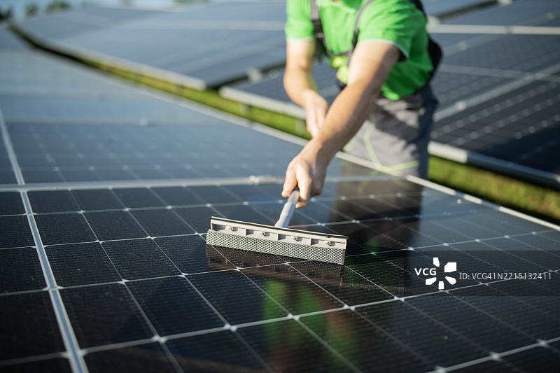 用窗户清洁剂清洁太阳能电池板。图片素材