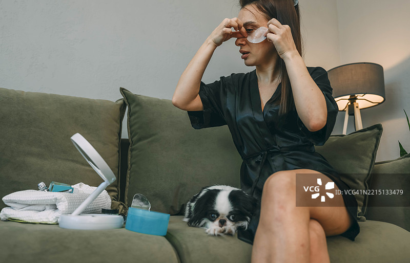 穿着黑色长袍的女性在家中早晨美容时光中使用眼部贴片图片素材