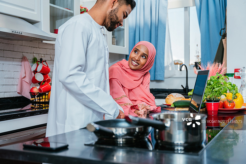 快乐的中东夫妇穿着传统阿拉伯服装在家中，阿拉伯联合酋长国图片素材