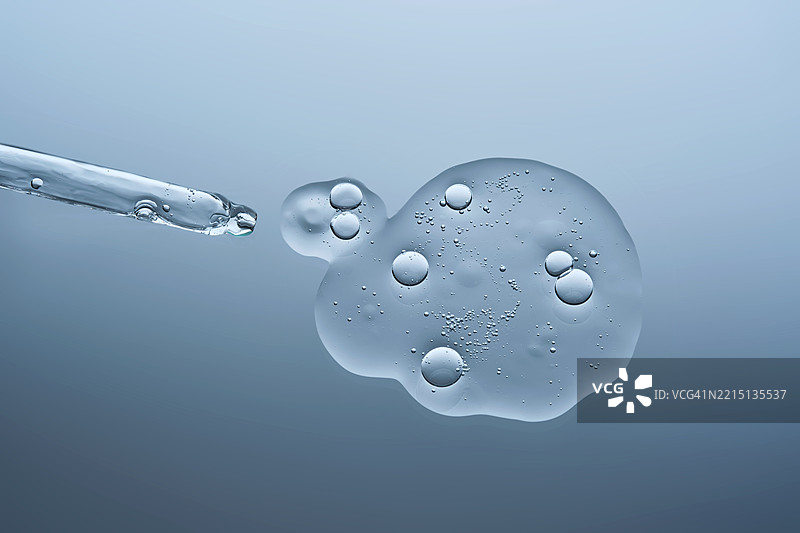 透明的精华液与气泡和滴管在蓝色背景上图片素材