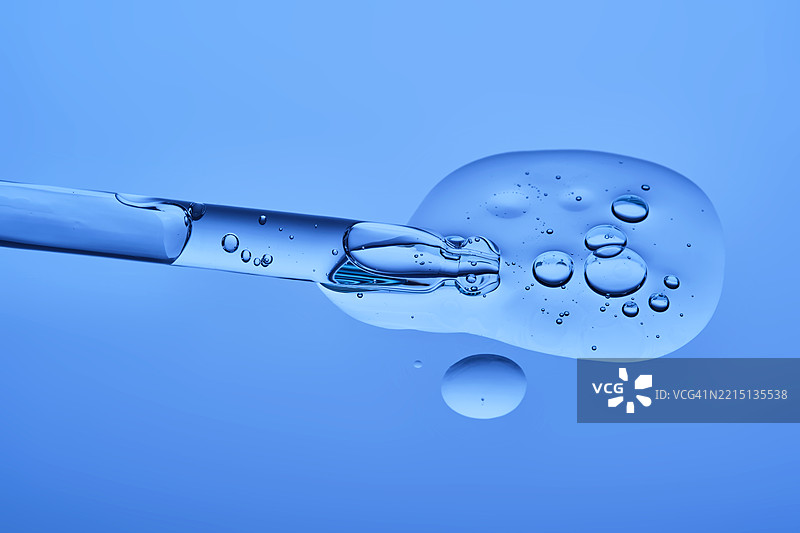 蓝色背景上的含肽精华液与滴管，质地细腻图片素材