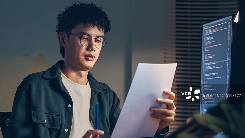 白人程序员或IT专家软件开发人员正在双屏电脑上查看基于视觉图表、图解和设计线框的代码设计，进行集成和开发。图片素材