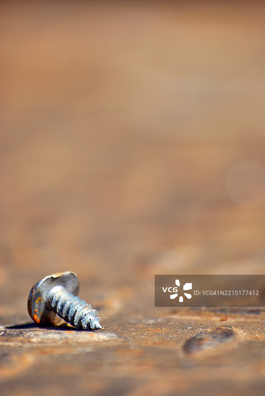 一颗生锈的旧螺丝钉，上面有一个凹痕。图片素材