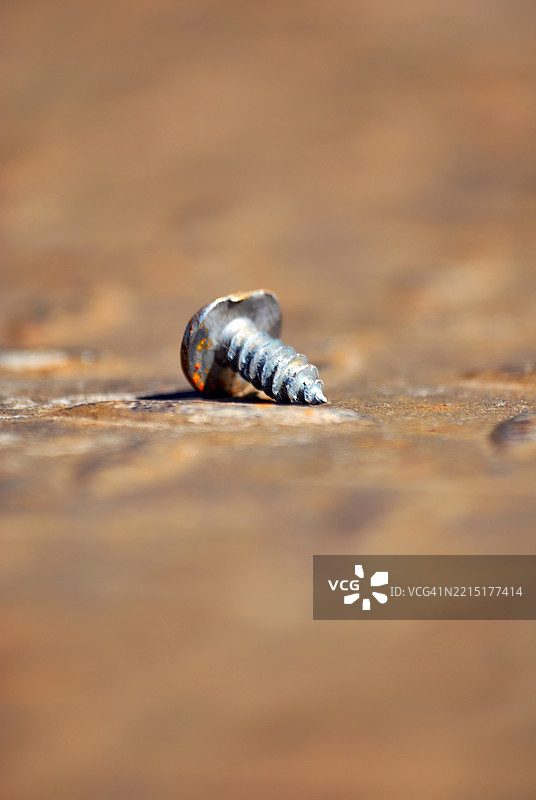 一颗生锈的旧螺丝钉，上面有一个凹痕。图片素材