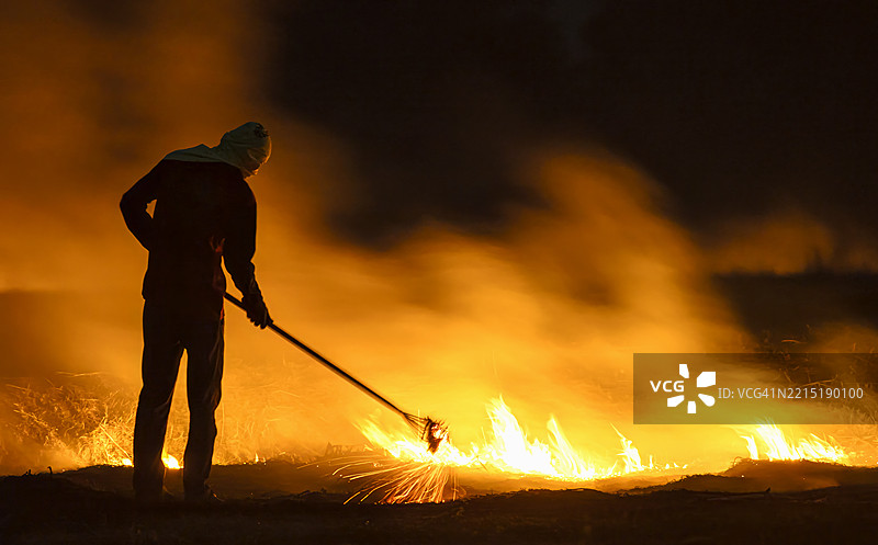 农民在燃烧稻草，背景是燃烧的稻草和照亮的烟雾云，这是气候变化、全球变暖、极端天气和全球高温的后果。图片素材