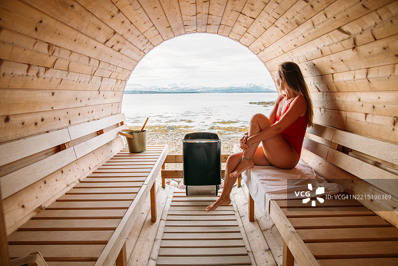 在木质桑拿中放松的女性，俯瞰美丽的海景图片素材
