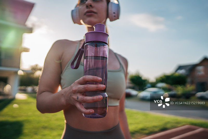 年轻的运动女性在户外训练后喝水图片素材