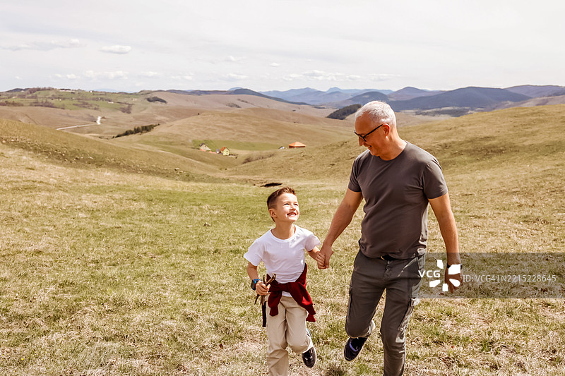 父亲和儿子在阳光明媚的乡村风景中散步图片素材