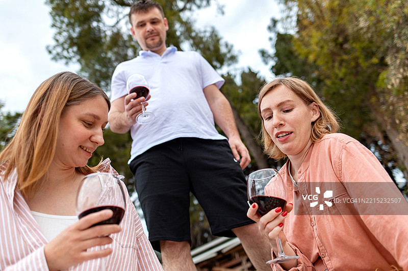三位朋友在户外放松，手持酒杯，享受这一刻图片素材