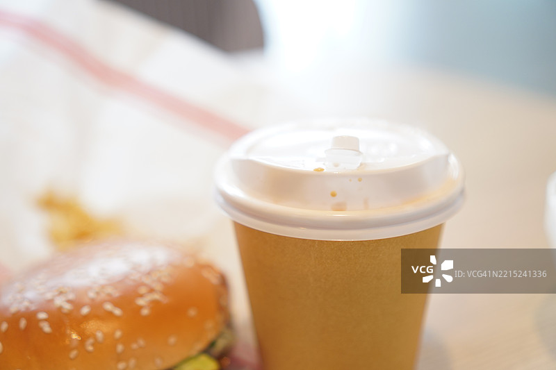 纸杯中的热咖啡，木桌上的汉堡和猪肉图片素材