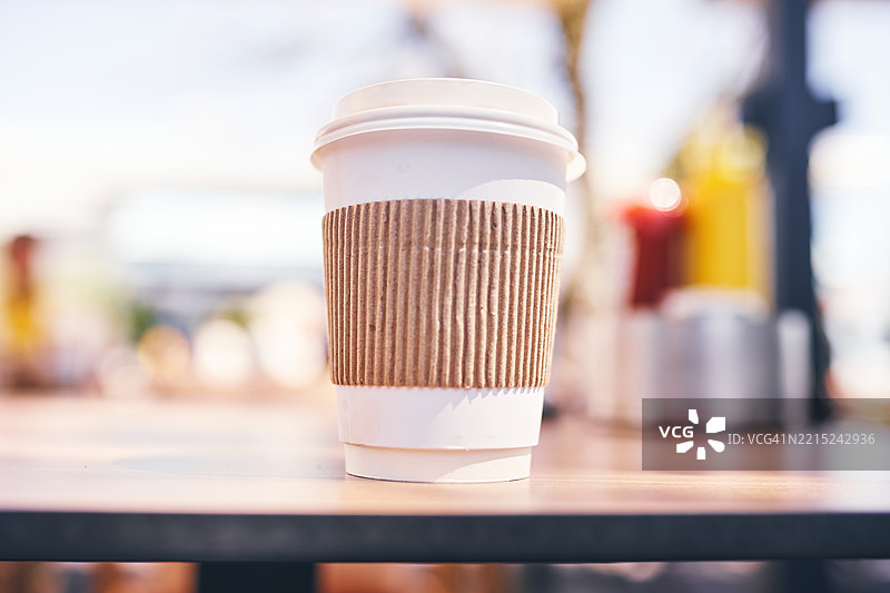 户外自然光下木桌上的一次性咖啡杯图片素材