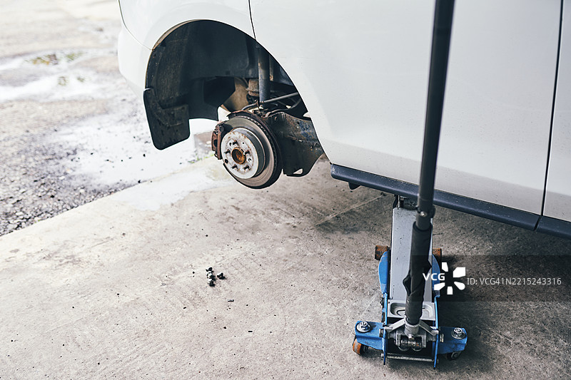 汽车被抬起进行维护，刹车转子清晰可见，稳定的千斤顶支撑着。图片素材