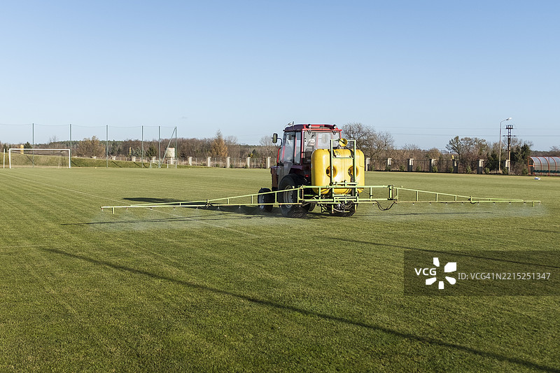 施肥拖拉机在足球场上喷洒肥料图片素材