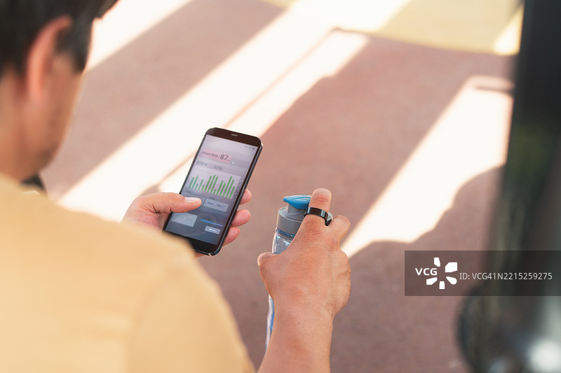 户外健身房中佩戴智能戒指和使用智能手机的男子图片素材
