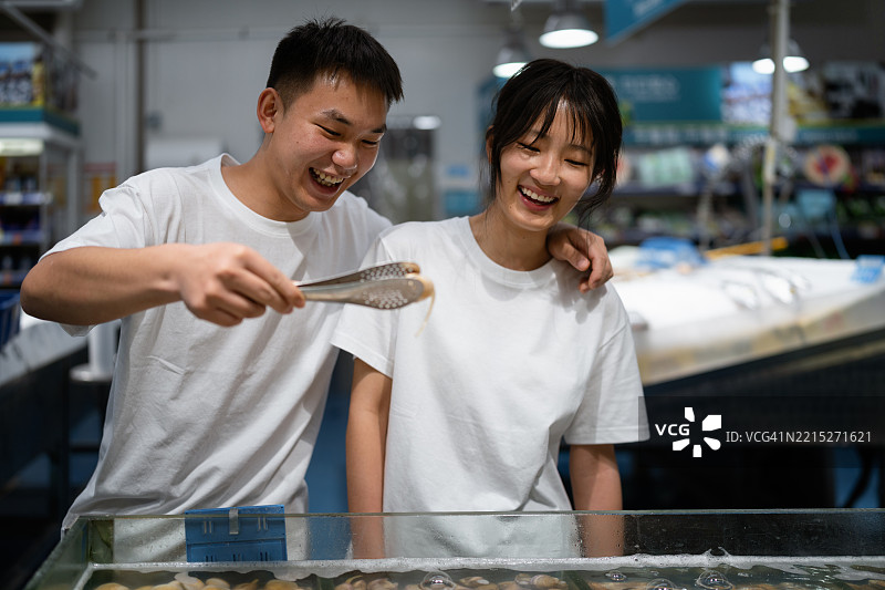 快乐的情侣在超市购买鱼类图片素材